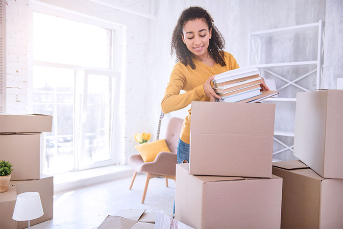Curly haired girl packing books before moving out