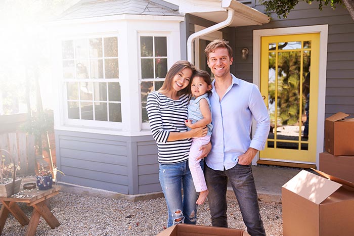 Young family standing outside new home