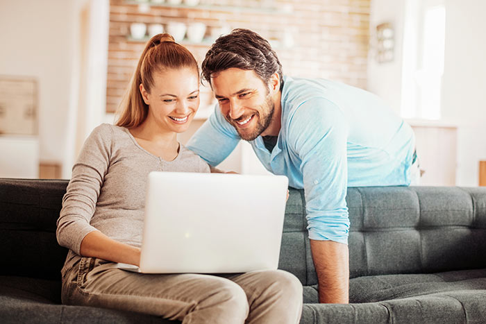 Happy young couple using laptop at home