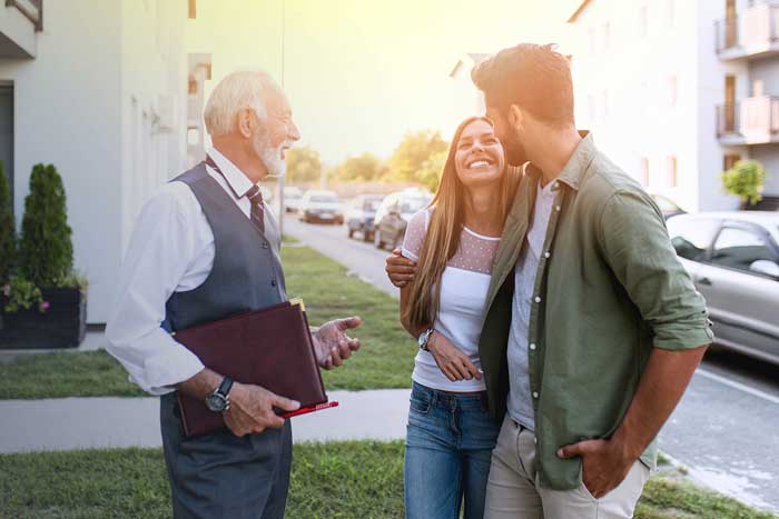 Young couple talking with real estate agent and buying a new house