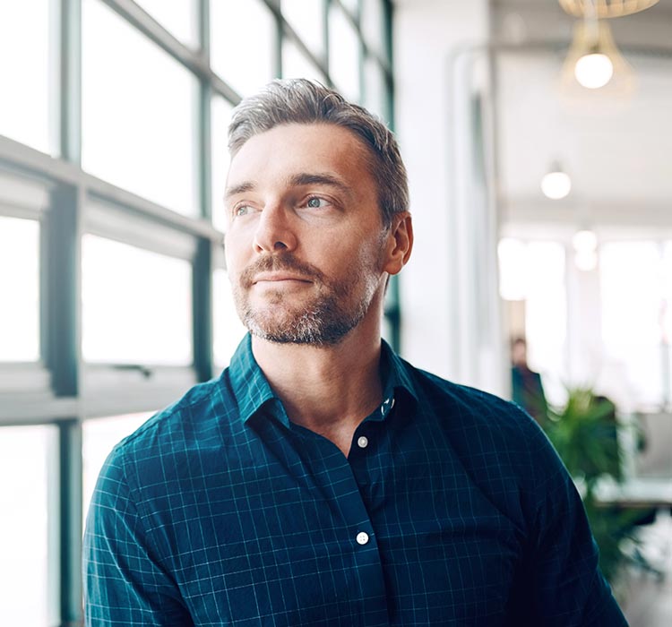 Mature businessman looking thoughtfully out of an office