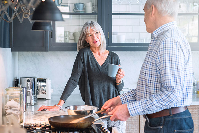 Senior couple in a kitchen making dinner and talking