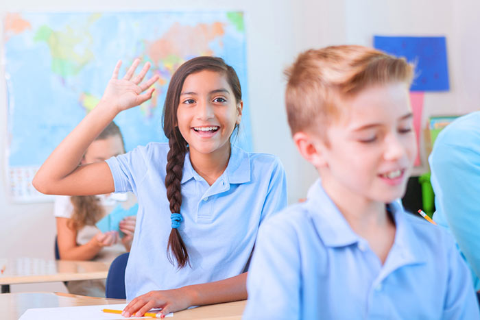 Young girl raises her hand in classroom