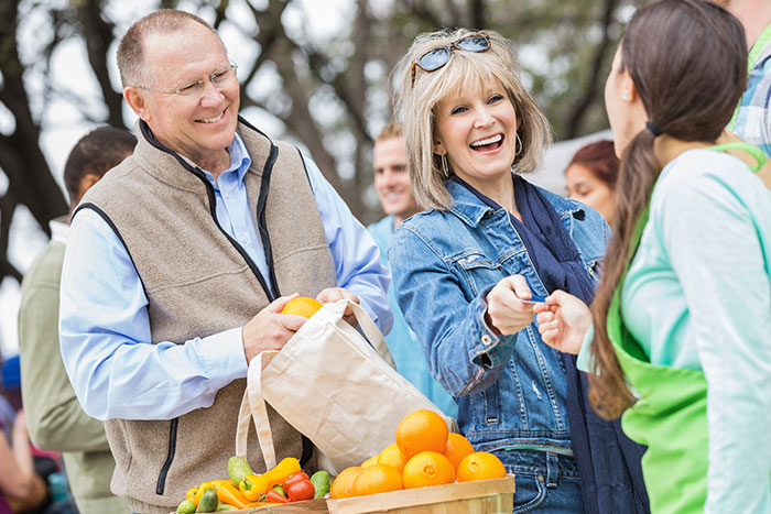 Happy senior woman paying for produce at local farmers market