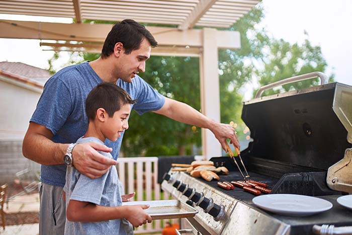 Father teaching son how to grill