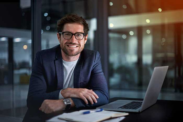 Happy young businessman working at his office desk