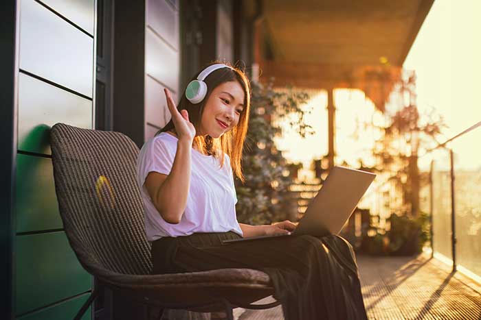 Young woman with headphones having conference call on laptop