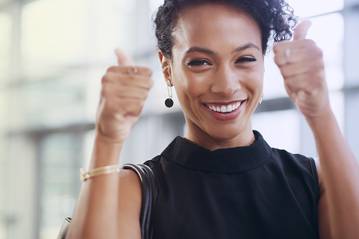 Cropped shot of a young businesswoman showing thumbs up while walking through a modern office