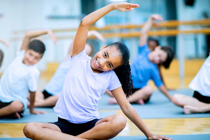 A group of school children are indoors in the gym exercising