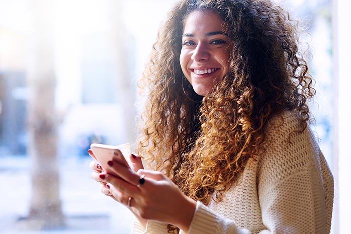 Cheerful young woman with curly hair spending time in cafe