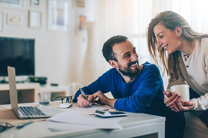 Couple sitting in their living room and checking their finances
