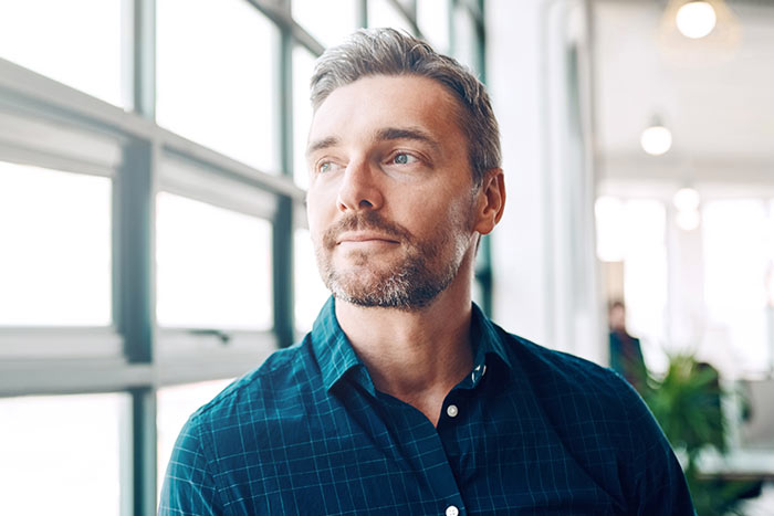 Mature businessman looking thoughtfully out of an office