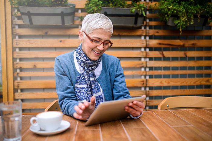 Smiling mature woman using digital tablet while drinking a coffee