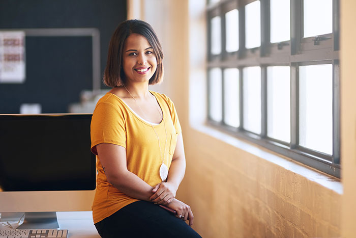 Teacher leaning on a desk in her class