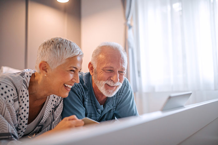 Happy senior couple shopping online in bed