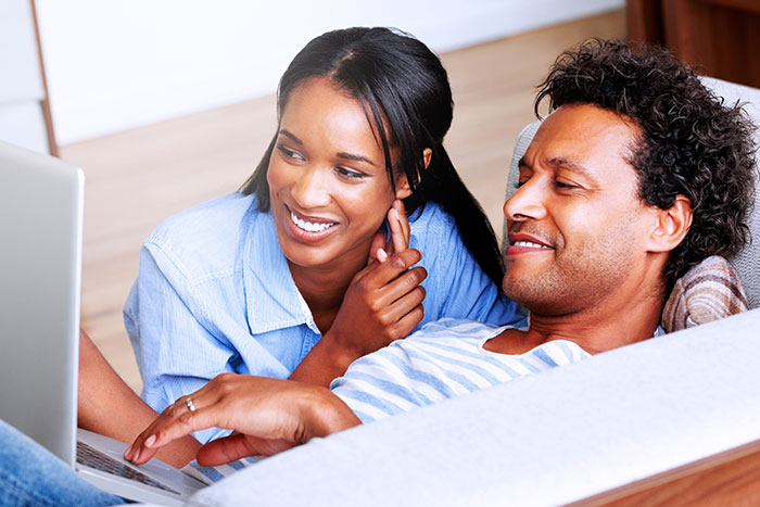 Happy couple relaxing on couch with laptop