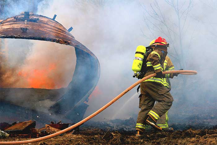 Full geared firefighter with water hose on field