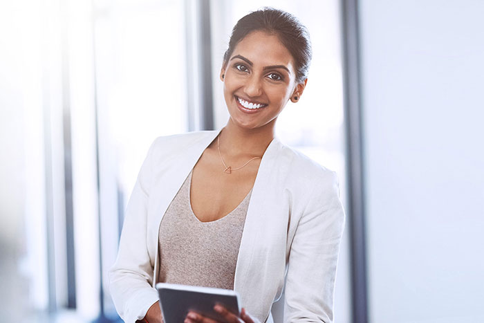 Smiling young Indian woman using tablet in office