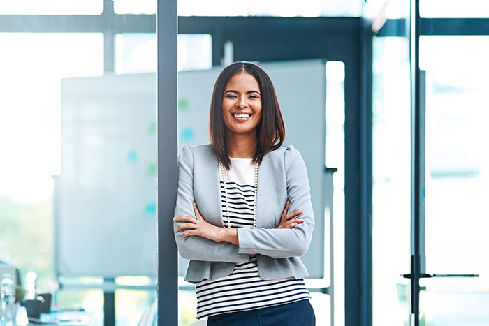 Lady smiling, crossing hands and leading on a glass door.