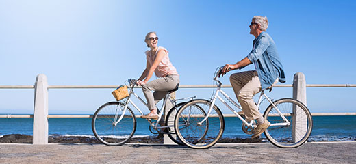 Happy couple going for a bike ride on the pier on a sunny day