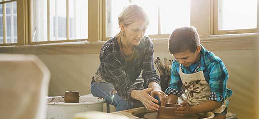 Female teacher assisting boy in pottery class
