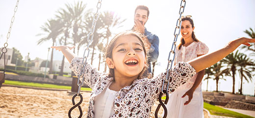 Little girl playing on the swing with her mom and father