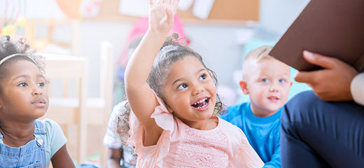 Little girl raises her hand in class