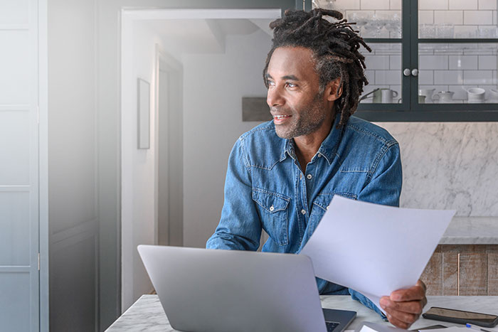 Confident businessman in his 50s working on laptop and paperwork