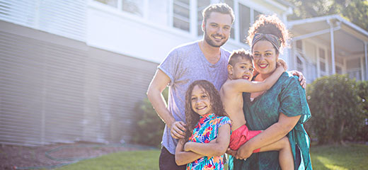 Family standing outside of the house and smiling.