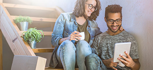 Young couple sitting on stairs watching ipad